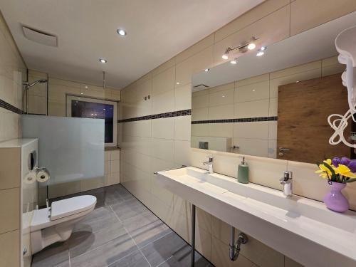 ein Badezimmer mit zwei Waschbecken, einem WC und einem Spiegel in der Unterkunft FeWo Regenbogen in Friedrichshafen