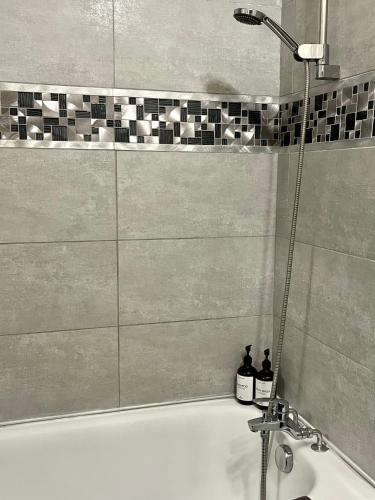 - une baignoire avec douche et 2 bouteilles dans l'établissement Appartement 12 min Paris - Parking Privé Gratuit - Wifi - Netflix - Balcon, à Enghien-les-Bains