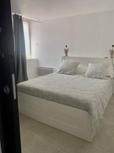 un lit blanc dans une chambre blanche avec une fenêtre dans l'établissement Maison de ville très lumineuse au centre ville, à Dax