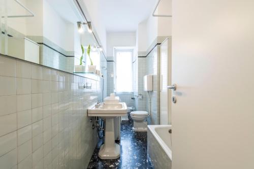 La salle de bains blanche est pourvue d'un lavabo et de toilettes. dans l'établissement Victory Apartment, à Vérone