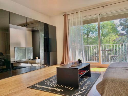 a living room with a bed and a large window at Cocon Parisien 12 min Paris - parking privé gratuit - Balcon - Wifi in Enghien-les-Bains
