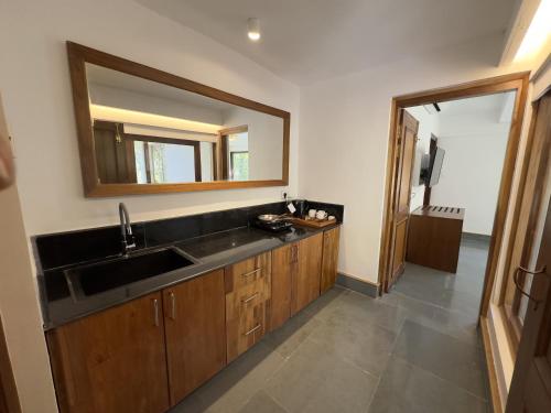 a bathroom with a sink and a mirror at Saraca Resort & Spa Corbett in Garjia
