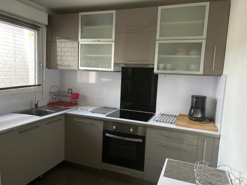 La cuisine est équipée de placards blancs et d'un four avec plaques de cuisson noires. dans l'établissement Entre Paris et Disneyland, à Chelles