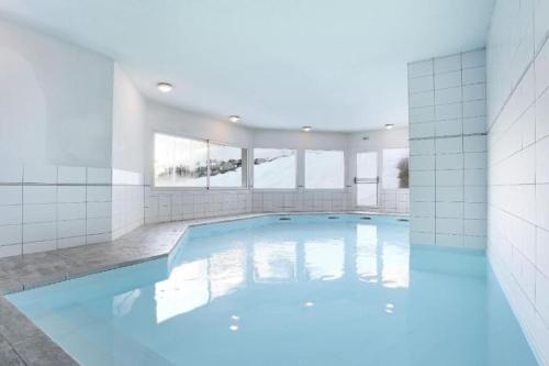 une grande piscine avec de l'eau bleue dans un immeuble dans l'établissement Charmant appartement « Les belles roches » Piscine, à Notre-Dame-de-Bellecombe