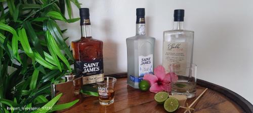 three bottles of alcohol and glasses on a wooden table at Le Voyageur in Sainte-Marie