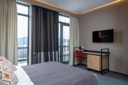 Una habitación de hotel con una cama y un escritorio con televisión. en Almendinger Bolnisi, en Bolnisi