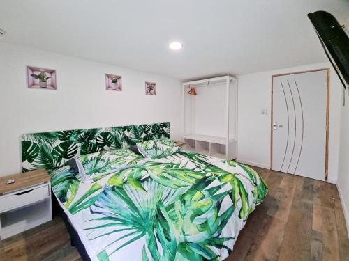 a bedroom with a bed with a green leaf bedspread at les piafs du der 1 in Joncreuil