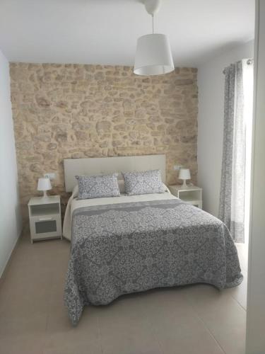 a bedroom with a bed and a brick wall at Casa Correos in Medina Sidonia