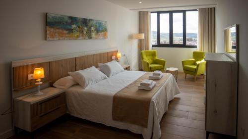 una camera da letto con un letto e due sedie verdi di Alojamientos VEN -Vista Extremadura Norte a Plasencia
