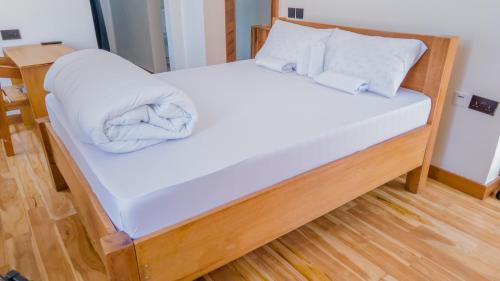uma cama com lençóis brancos e almofadas em Nyitika Hotel em Mugumu