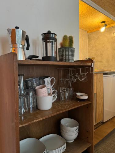 - une étagère en bois avec de la vaisselle et des ustensiles dans la cuisine dans l'établissement L’Atypique - centre Chamonix, à Chamonix-Mont-Blanc