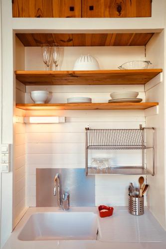 - une cuisine avec un évier blanc et des étagères en bois dans l'établissement Artelier 32 - Lyon Tête d'Or, à Lyon