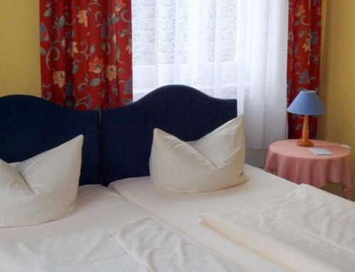 ein Schlafzimmer mit einem Bett mit weißen Kissen und einem Fenster in der Unterkunft Gästehaus Vis-A-Vis in Rüdesheim am Rhein