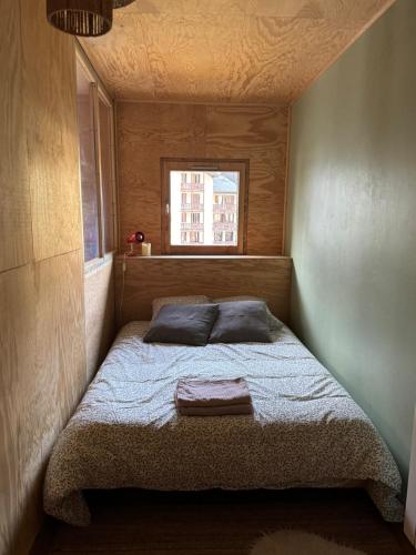 un lit dans une petite pièce avec une fenêtre dans l'établissement L’Atypique - centre Chamonix, à Chamonix-Mont-Blanc