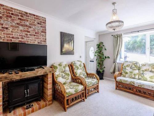 a living room with two chairs and a flat screen tv at Forest side cottage in Nottingham