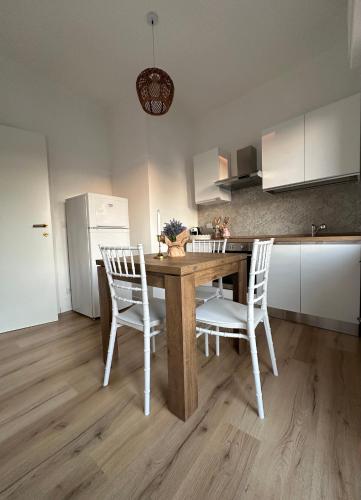 a kitchen with a wooden table and white chairs at Casa di Maya in Portacomaro