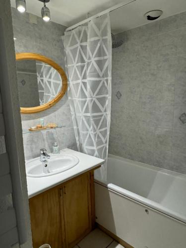 une salle de bain avec un lavabo, une baignoire et un miroir dans l'établissement L’Atypique - centre Chamonix, à Chamonix-Mont-Blanc