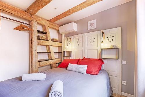 Schlafzimmer mit einem Bett mit roten Kissen und einer Leiter in der Unterkunft BREDALA**** Gîte maison Alsacienne avec Jardin in Eguisheim