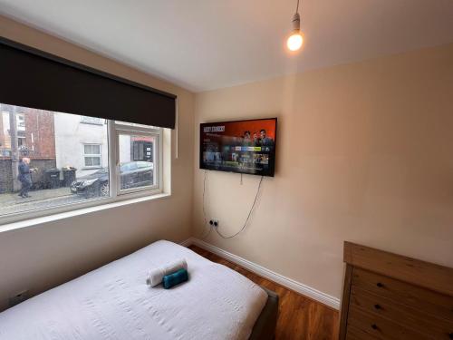 a bedroom with a bed and a tv on the wall at High-End Central Luton Studio - Ideal for Airport! in Luton