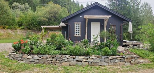 a small shed with a stone wall in front of a garden at Gurus Of Gravel Bike Retreat Guest Suite in Clearwater