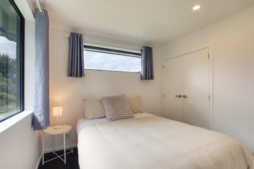 a small bedroom with a bed and a window at Stylish 4 Bedroom house Brand New in Rotorua in Rotorua
