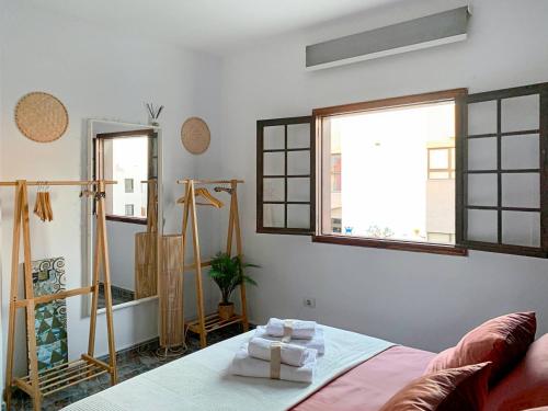 um quarto com uma cama e algumas janelas em Habitaciones privadas cerca de la playa y aeropuerto en casa compartida con otros huéspedes em Playa Honda