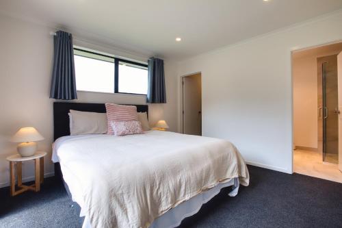a bedroom with a large white bed with a window at Stylish 4 Bedroom house Brand New in Rotorua in Rotorua