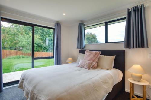 ein Schlafzimmer mit einem Bett und einem großen Fenster in der Unterkunft Stylish 4 Bedroom house Brand New in Rotorua in Rotorua