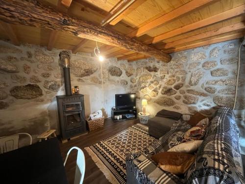 uma sala de estar com um sofá numa parede de pedra em Casa da Serra da Estrela em Gonçalo