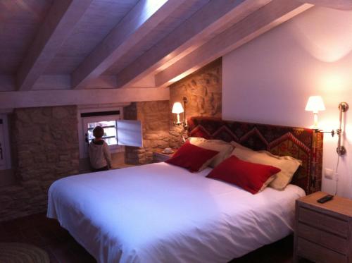 1 dormitorio con 1 cama blanca grande con almohadas rojas en Hotel El Cerco en Puente la Reina
