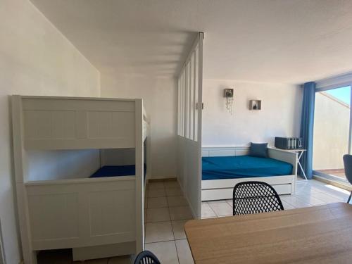 ein kleines Schlafzimmer mit einem Etagenbett und einem Tisch in der Unterkunft Appart 5 min à pied de la plage in Cap d'Agde