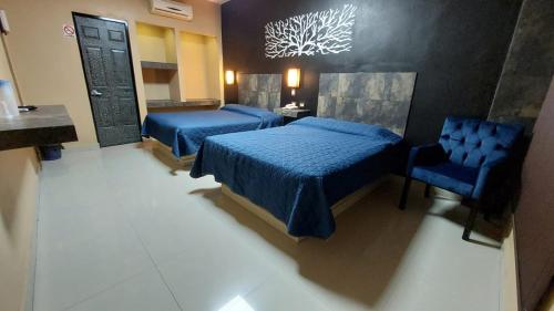 a hotel room with two beds and a chair at Hotel La Silla in Monterrey