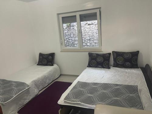 two beds in a room with a window at Cuprija _apartments in Stolac