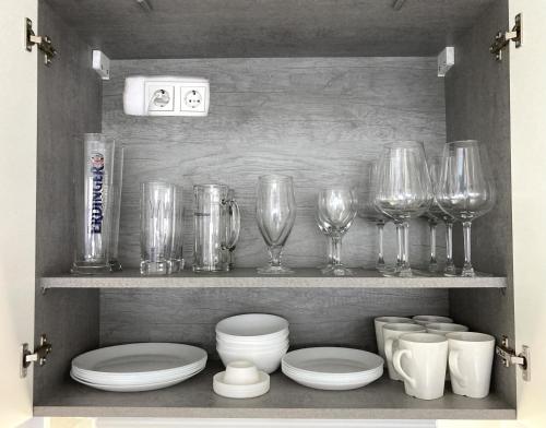 a shelf with wine glasses and plates and bowls at Living at Saarpartments - Business & Holiday Apartments with Netflix for Long- and Short term Stay, 3 min to St Johanner Markt and Points of Interest in Saarbrücken