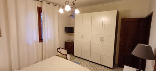 - une chambre avec un lit blanc et une armoire dans l'établissement Casa Mary, à Giardini Naxos