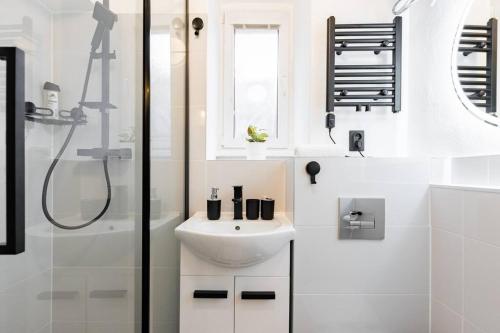 a white bathroom with a sink and a shower at Central Serenity: Urban Garden Retreat in Bratislava