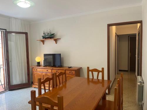 a dining room with a wooden table and a television at Apartamento céntrico, bien equipado y tranquilo, a 350m de la playa por Rambla Vidal in Sant Feliu de Guixols