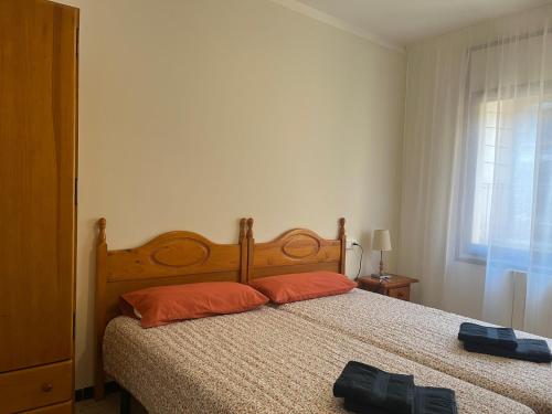 a bedroom with a bed with orange pillows and a window at Apartamento céntrico, bien equipado y tranquilo, a 350m de la playa por Rambla Vidal in Sant Feliu de Guixols
