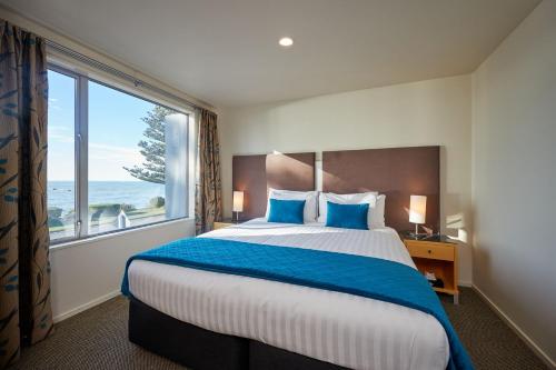 1 dormitorio con 1 cama grande y ventana grande en Waves on Esplanade - Kaikoura Waterfront Apartment, en Kaikoura