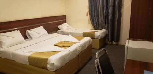 a hotel room with two beds and a chair at قلف الرائدة رحاب التصنيف نجمة واحده in An Naqāʼ