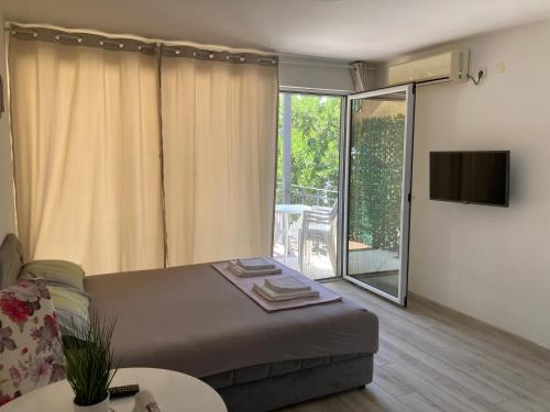 sala de estar con cama y puerta corredera de cristal en Budva, Jaz, apartmani DIF en Budva