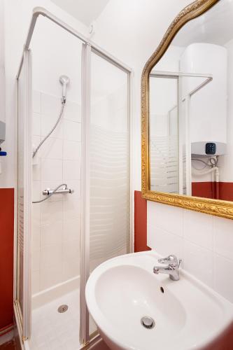 une salle de bain avec un lavabo et une douche avec un miroir dans l'établissement Guestrust - Arc de Triomphe 46, à Paris