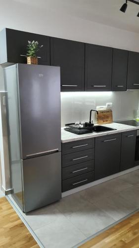a kitchen with black cabinets and a stainless steel refrigerator at JR Lux apartman in Stara Pazova