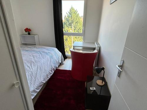 Habitación pequeña con cama y silla roja. en Chic Appart LYON - Chambre chez l'habitant, en Saint-Fons