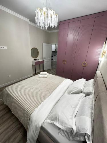 een slaapkamer met een groot bed met een paarse muur bij ЖК2 Estet 157 in Alma-Ata