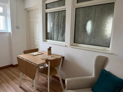 a dining room with a table and chairs and two windows at Home close to SW Coastal path in Hartland