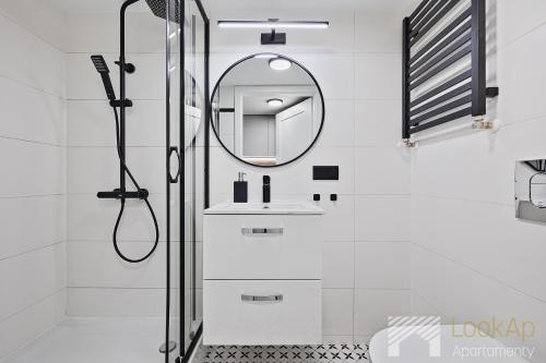 a white bathroom with a shower and a mirror at U Fabrykanta by LookAp in Łódź
