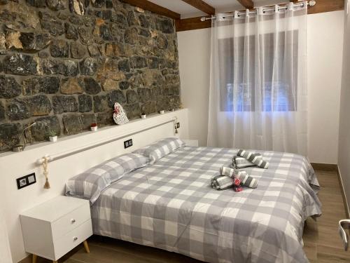 a bedroom with a bed and a stone wall at Apartamentos Iramar in Ramales de la Victoria