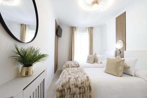 two beds in a white room with a mirror at Apartamento Exclusivo Centrico con parking in Ribadeo