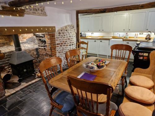 a kitchen with a wooden table and a fireplace at Delightful 3bed thatched Cottage in Stockbridge